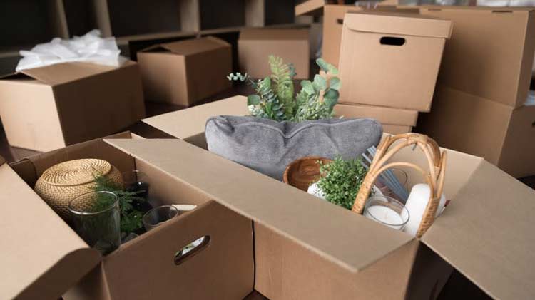 Cardboard boxes stacked up and some with vases, fake plants, and candles showing