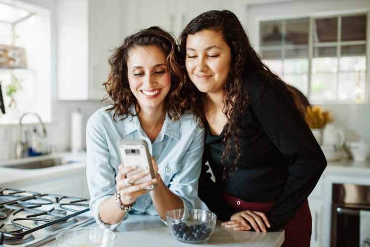 A mother and daughter smiling while looking at party options