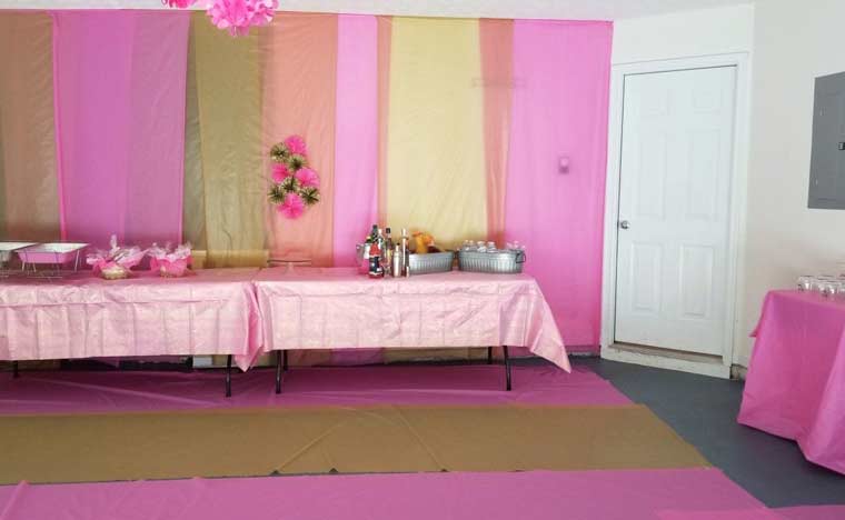 Tablecloths in pink and gold are hung on walls and placed on the ground at grad party