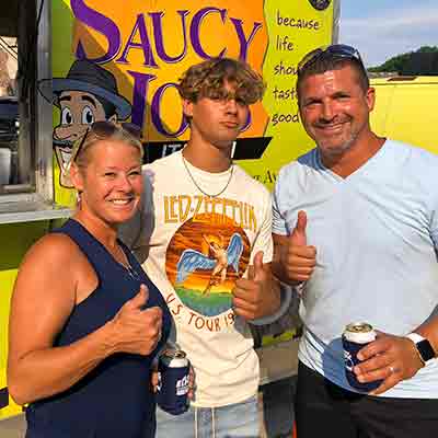 Parents and grad giving thumbs up in front of Saucy Joe's Food Truck