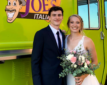 Newlyweds Smiling in front of Saucy Joe's Food Truck